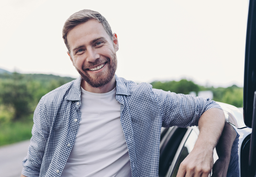 smiling man leaning on a car